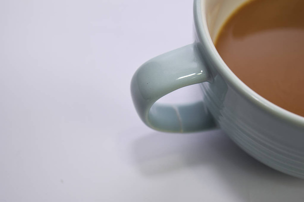 白い背景に隔離された青いカップでホットカプチーノコーヒーをクローズアップ - 写真・画像