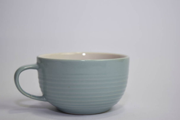 Κλείστε τον ζεστό καφέ καπουτσίνο σε ένα μπλε φλιτζάνι απομονωμένο σε λευκό φόντο - Φωτογραφία, εικόνα