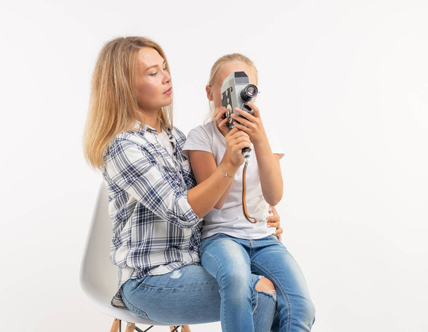 Foto, fotograf a retro fotoaparát koncept - mladá žena a její dcera pomocí vinobraní fotoaparát na bílém pozadí - Fotografie, Obrázek