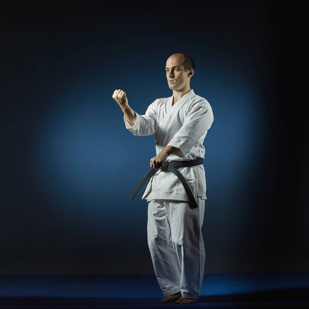 Atlet mavi bir tatami üzerinde resmi karate egzersizleri gerçekleştirir - Fotoğraf, Görsel