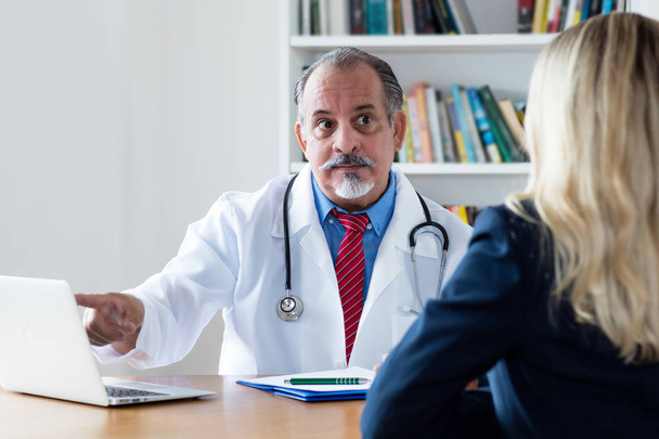 General practitioner explaining diagnosis to female patient - Foto, afbeelding