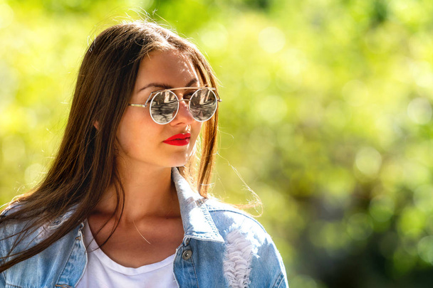 Outdoor portrait of beautiful, emotional, young woman in sunglasses. Soft background. Copy space. - Fotó, kép