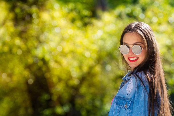 Outdoor portrait of beautiful, emotional, young woman in sunglasses. Soft background. Copy space. - Photo, image