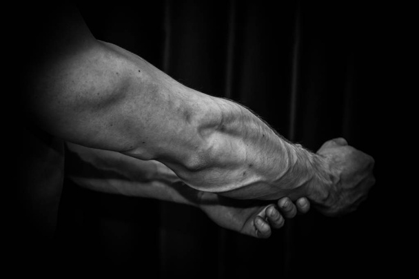 athlete shows pumped hand close-up on a black background. bodybuilding mr. olympia - Foto, Imagem