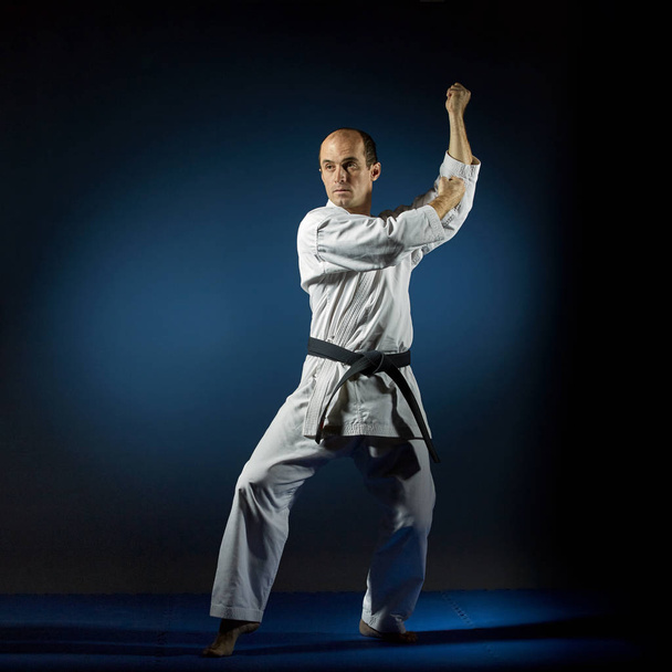 Aktywny sportowiec trenuje formalne ćwiczenia Karate na niebieskim tatami - Zdjęcie, obraz