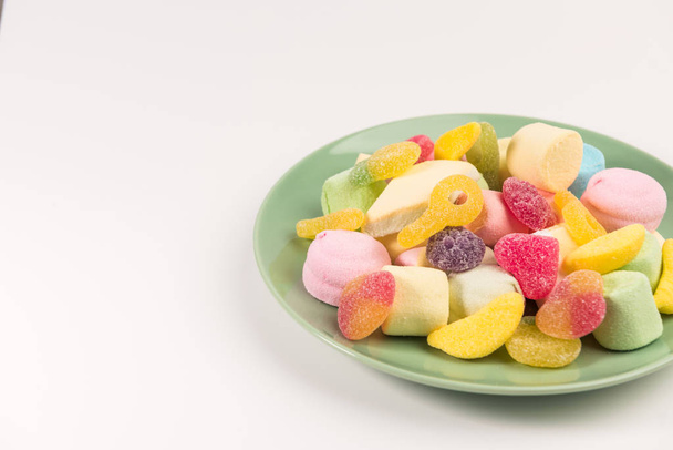 Plate with sweets isolated on a white background. Gummy candies and marshmallow. - Фото, зображення