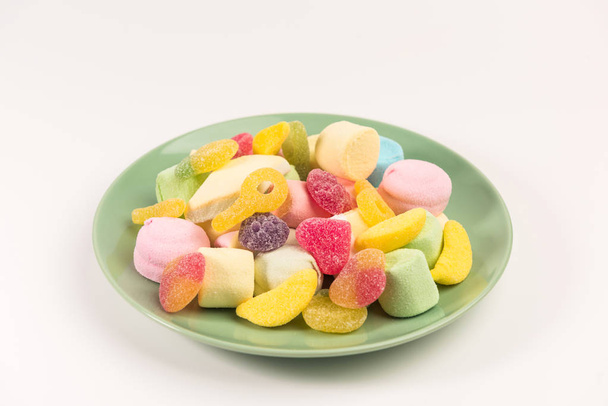 Assiette avec des bonbons isolés sur un fond blanc. Bonbons gommeux et guimauve
. - Photo, image