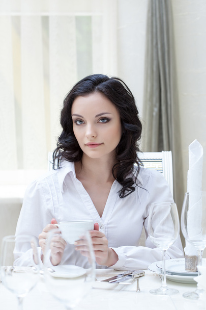 Portrait of attractive brunette sitting at table - 写真・画像
