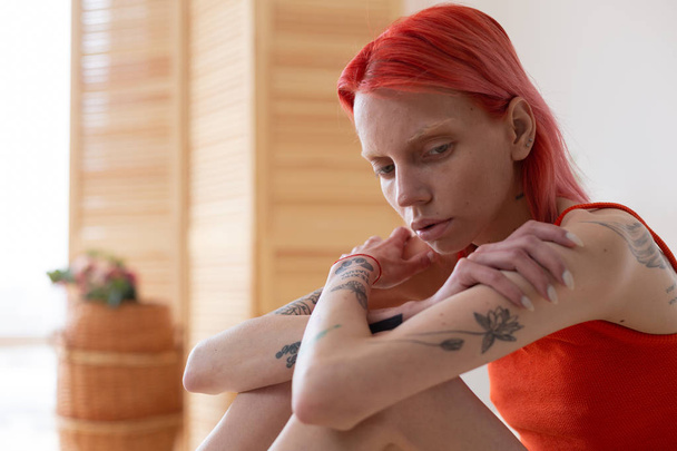 Рудоволоса анорексична жінка з татуюваннями відчуває себе самотньою і сумною
 - Фото, зображення