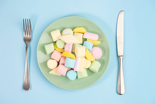 Fork, knife and Green plate with marshmallow. Top view. - Foto, Imagen