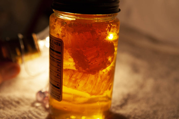 frischer Bernstein lokaler Honig in einem Glas mit Wachshonigwabenzellen innen - Foto, Bild