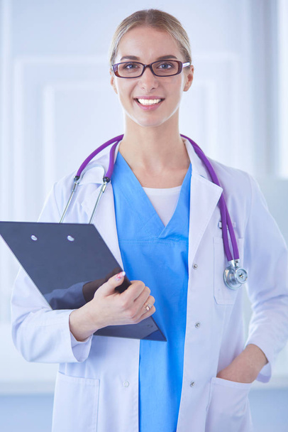 Smiling female doctor with a folder in uniform standing - Fotó, kép