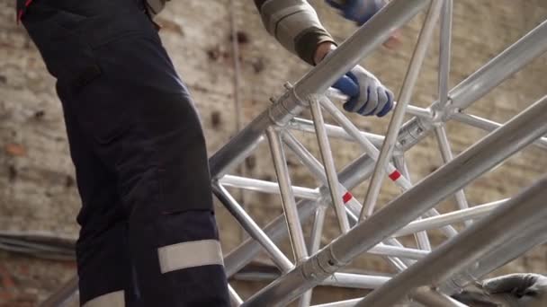 Spécialiste technique homme ajuste la structure de scène en aluminium gris avec marteau
 - Séquence, vidéo