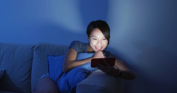 女性は家の中で夜に携帯電話で見る - 写真・画像