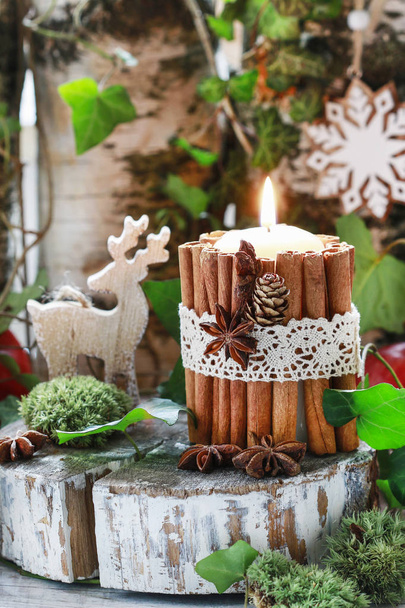 Candle decorated with cinnamon sticks, moss, ivy leaves and wood - Foto, Bild