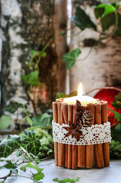 Candle decorated with cinnamon sticks, moss, ivy leaves and wood - Zdjęcie, obraz