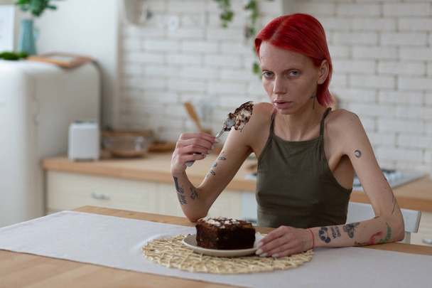 Woman with bulimia holding fork with big piece of cake - Zdjęcie, obraz