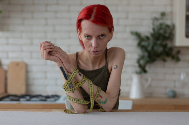 Donna anoressica con tatuaggi con metro a nastro sulle mani
 - Foto, immagini