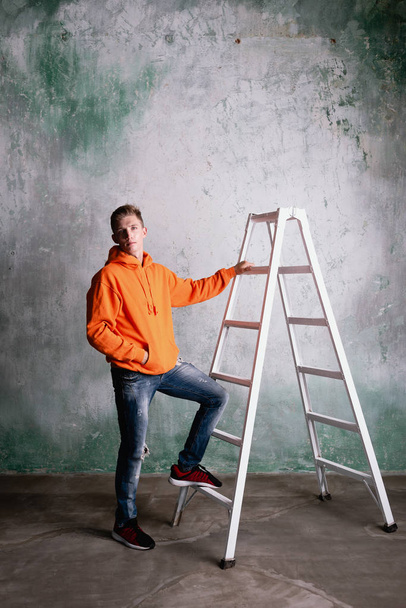 Mužský inženýr stojí na stavebním žebříku. pracovní oděvy. - Fotografie, Obrázek