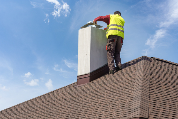 Άνθρωπος εγκατάσταση καμινάδα στην κορυφή της στέγης του νέου σπιτιού υπό κατασκευή - Φωτογραφία, εικόνα