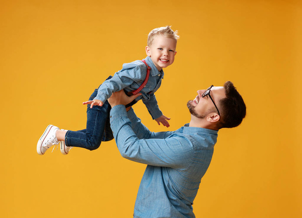 幸せな父の日!黄色のバックグローンに抱きしめるかわいいお父さんと息子 - 写真・画像