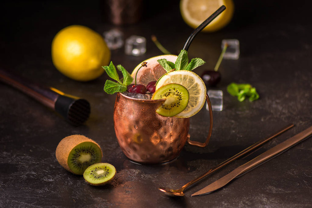 Exotic cocktail in copper mug (variation of Moscow mule) on the black stone background. Selective focus. Shallow depth of field. - Photo, image