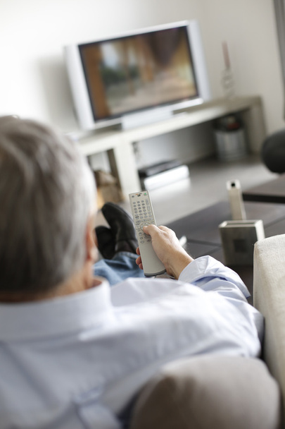 Widok starszy człowiek w kanapie przed telewizorem z tyłu - Zdjęcie, obraz