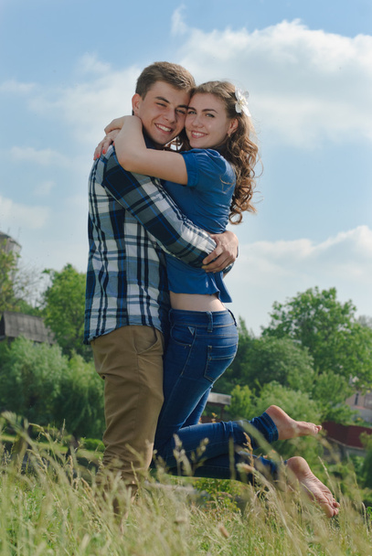 Happy teenage couple embracing over blue sky background - Foto, afbeelding