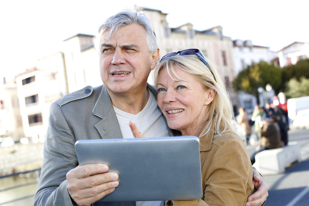 Senior couple using digital tablet in touristic area - 写真・画像