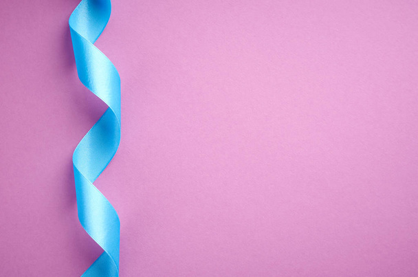 Blue ribbon on purple background composition, flat lay - Foto, imagen