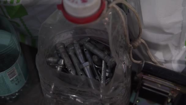 Műanyag palack tele van különböző alakú és méretű fém csapok és csavarok. - Felvétel, videó