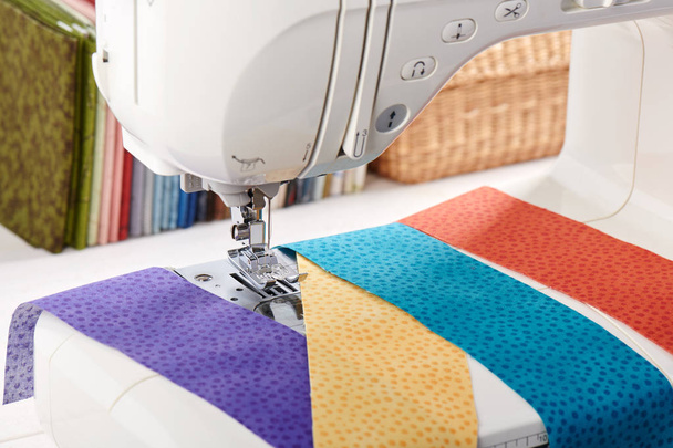 Sewing machine with a strips of fabrics on the background of stack of colorful quilting fabrics - Φωτογραφία, εικόνα