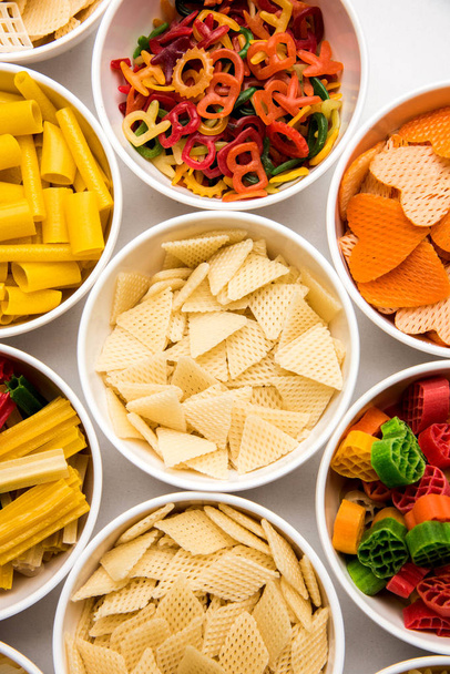 スナックペレットは、穀物、ジャガイモ、野菜粉末などの原料で作られた非拡張製品で、後にフライドポテト、ホットエアベーキングを使用して処理されます。多色/形のすぐに食べられるスナック - 写真・画像
