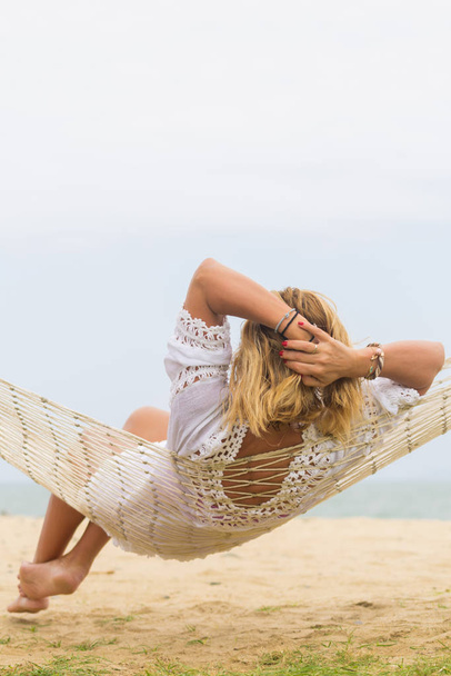 Woman sitting in hammock on the beach.  - Фото, зображення