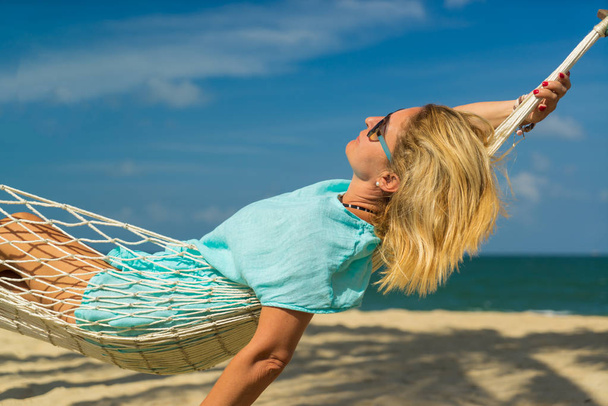 Woman sitting in hammock on the beach.  - Фото, изображение