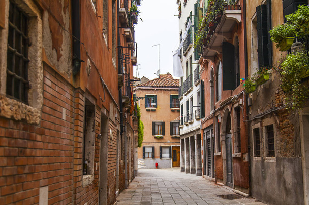 Venice, Italy, on April 25, 2019. Picturesque narrow street typical for Venice, architectural complex of old houses - Fotó, kép