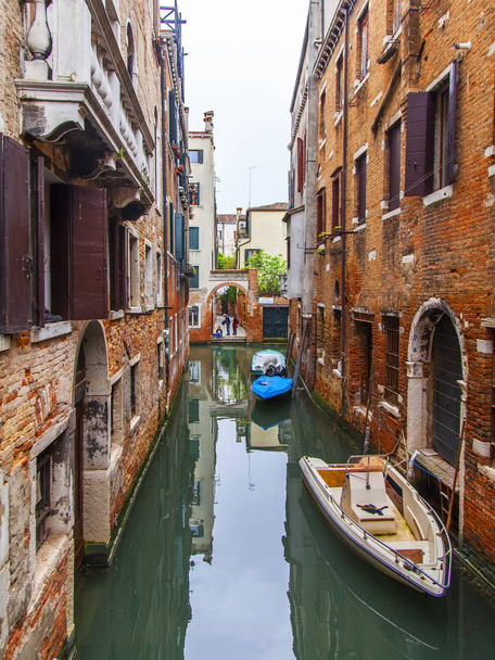 Venice, Italy, on April 25, 2019. Typical Venetian canal street and old buildings ashore - 写真・画像