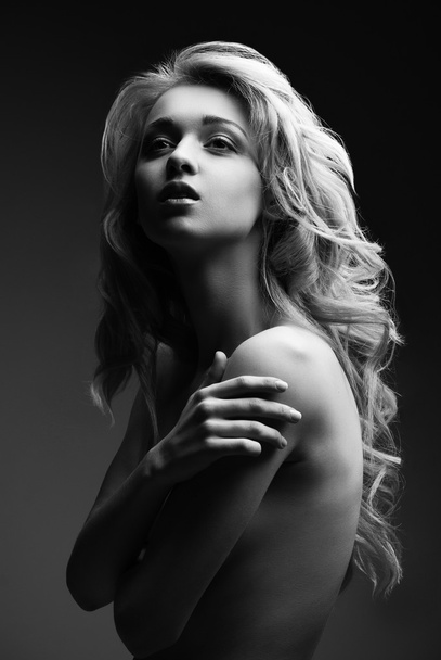 Posing blond woman with long curly hair on black - Foto, afbeelding