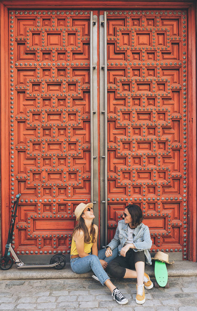 Jovens mulheres casal gay olhando e sorrindo uns aos outros em um fundo da porta vermelha. Felicidade do mesmo sexo e conceito alegre
. - Foto, Imagem