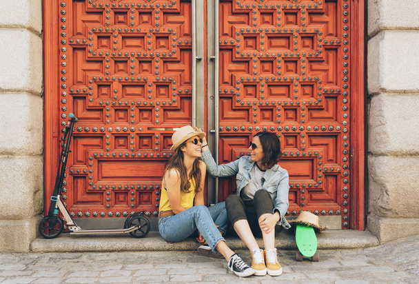 Fiatal nők meleg pár nézik és mosolyognak egymást egy piros ajtós háttérben. Ugyanaz a nemi boldogság és örömteli fogalom. - Fotó, kép
