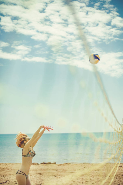eine junge schöne Dame spielt Volleyball am Strand, Sommerzeit am Strand. - Foto, Bild