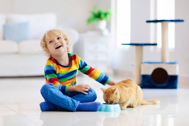 Kind spelen met kat thuis. Kinderen en huisdieren. - Foto, afbeelding