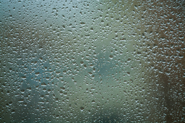 Тло або текстура. На віконному склі багато дрібних крапель дощу. Дощовий день весни
. - Фото, зображення