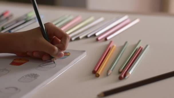 Hand van kleine meisje Coloring foto in een boek met gekleurd potlood op het Bureau, kunst en onderwijsconcept. - Video