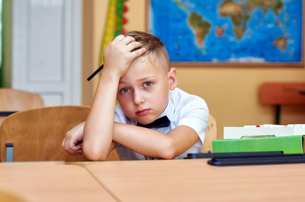 Portrait of a tired schoolboy in the classroom . Concept of education - Foto, afbeelding