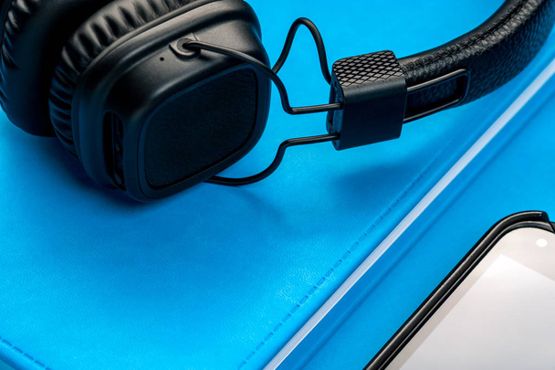 Black stylish headphones on blue background. - Foto, imagen