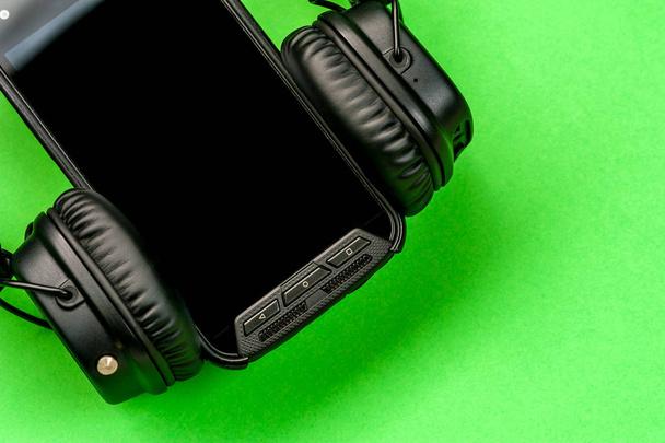 Black stylish headphones on green background. - Foto, imagen