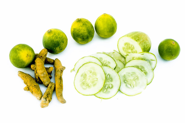 Cucumber face pack isolated on white i.e. Cucumber slices or cucumber pulp well mixed with turmeric powder and some lemon juice in a bowl and entire raw ingredients present with their reflection also. - Photo, Image