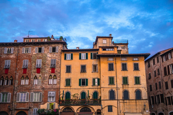 Typical traditional italian buildings on Piazza San Michele square in historical centre of old medieval town Lucca, evening view, Tuscany, Italy - Fotó, kép