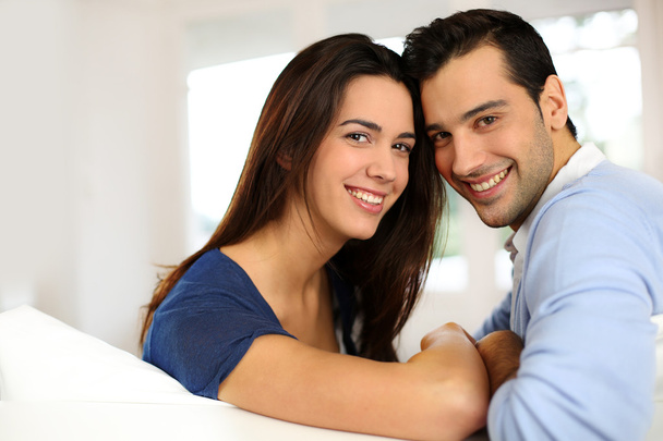 Portrait of cute young couple sitting in sofa - Foto, imagen